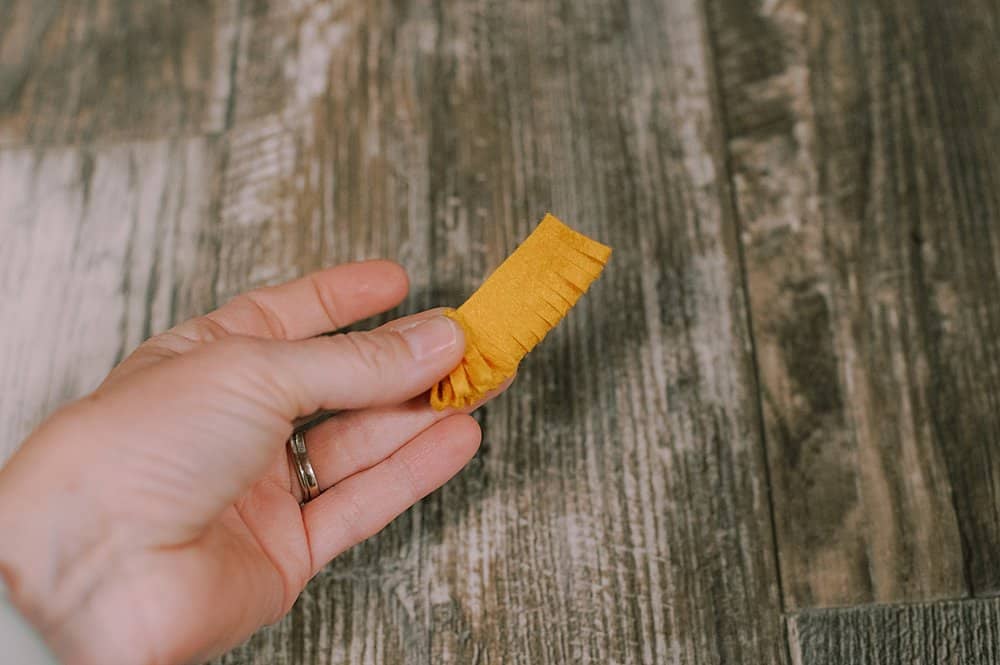 Yellow felt piece being rolled up in a hand.