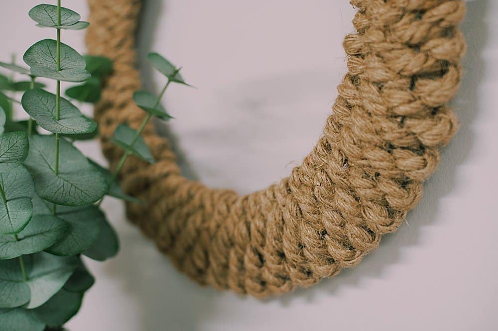 A photo showing the way a rope is weaved in and out of a wire wreath to make a front door wreath.