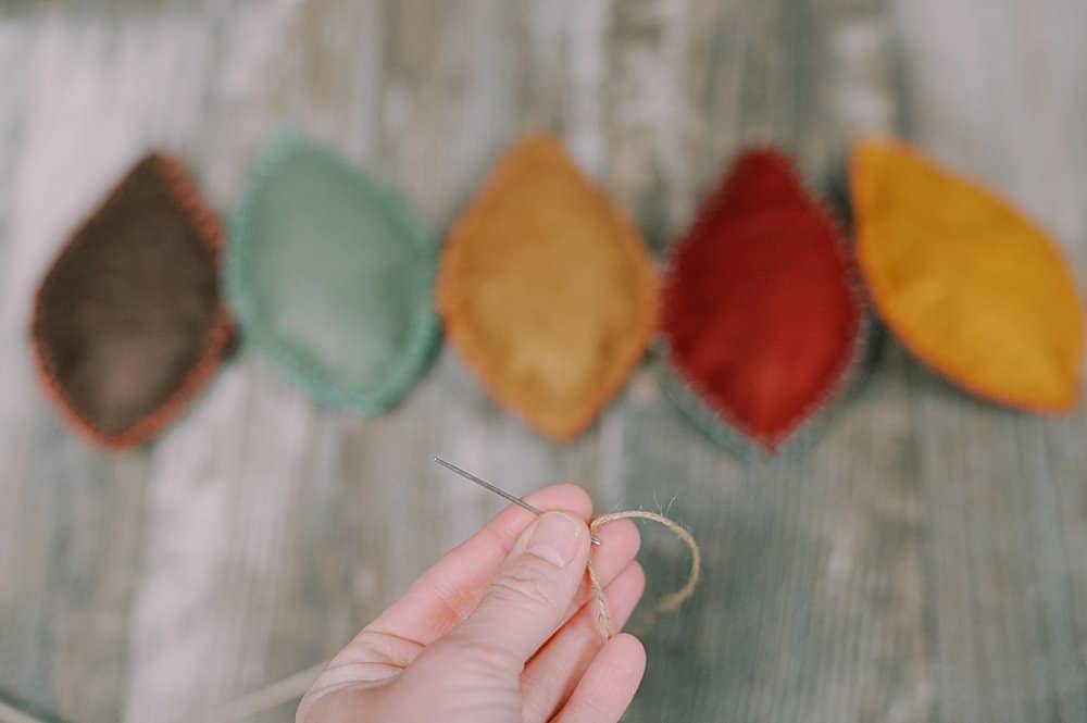 Learn how to make a felt leaf garland using felt leaves, stuffed with fiber fill and embroidered with a blanket stitch, and strung with twine!