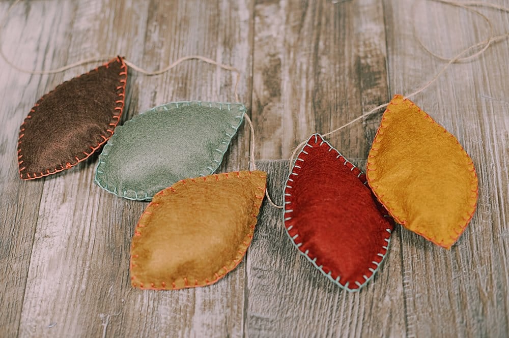 Learn how to make a felt leaf garland using felt leaves, stuffed with fiber fill and embroidered with a blanket stitch, and strung with twine!