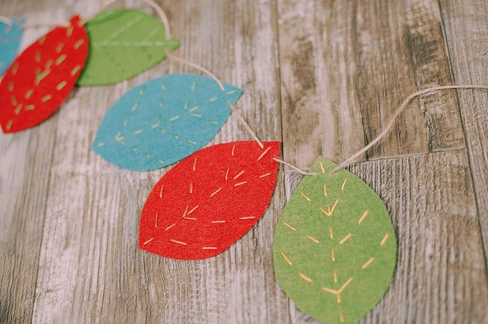 Learn how to make an embroidered felt leaf garland using felt leaves with embroidery floss veins, strung into a garland using twine!