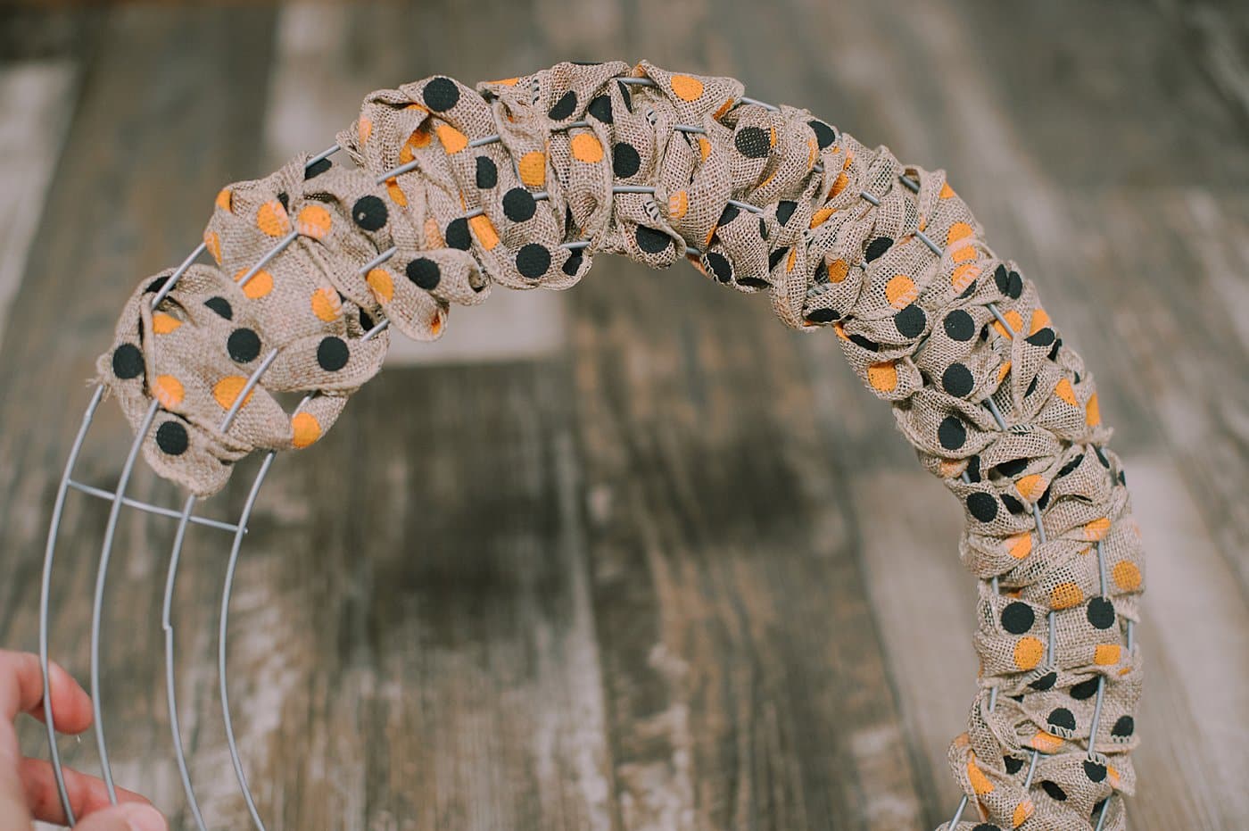 Continue to add more burlap ribbon to the halloween wreath.