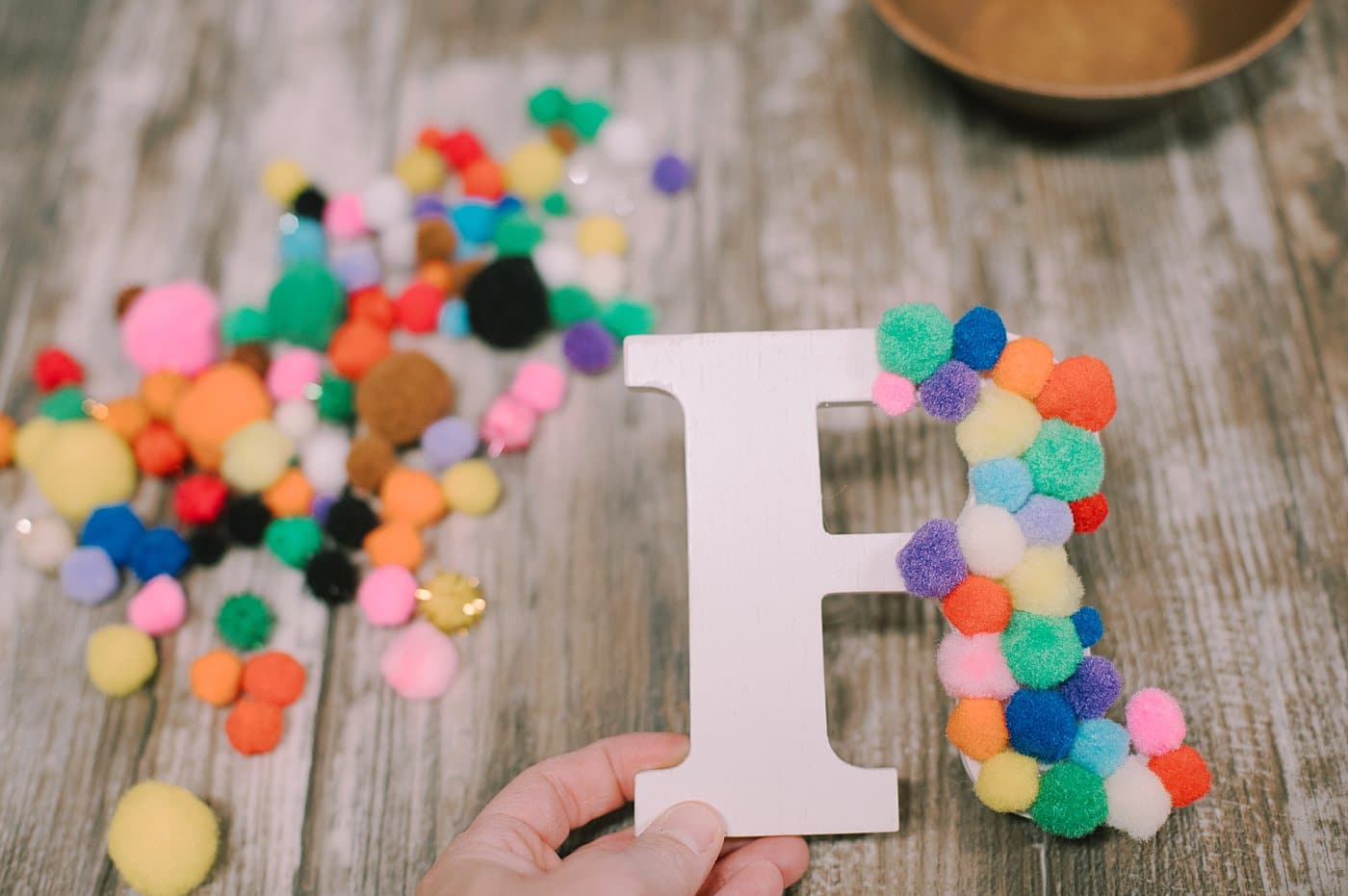Keep gluing pompoms onto a letter R.