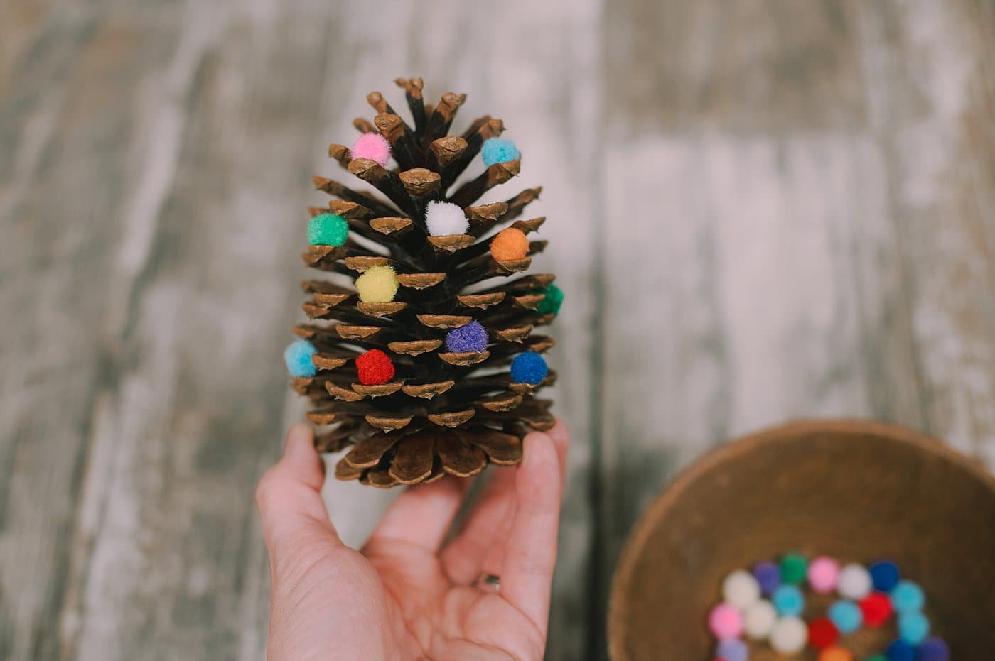 Continue to add pom poms to the edges of the pinecone.