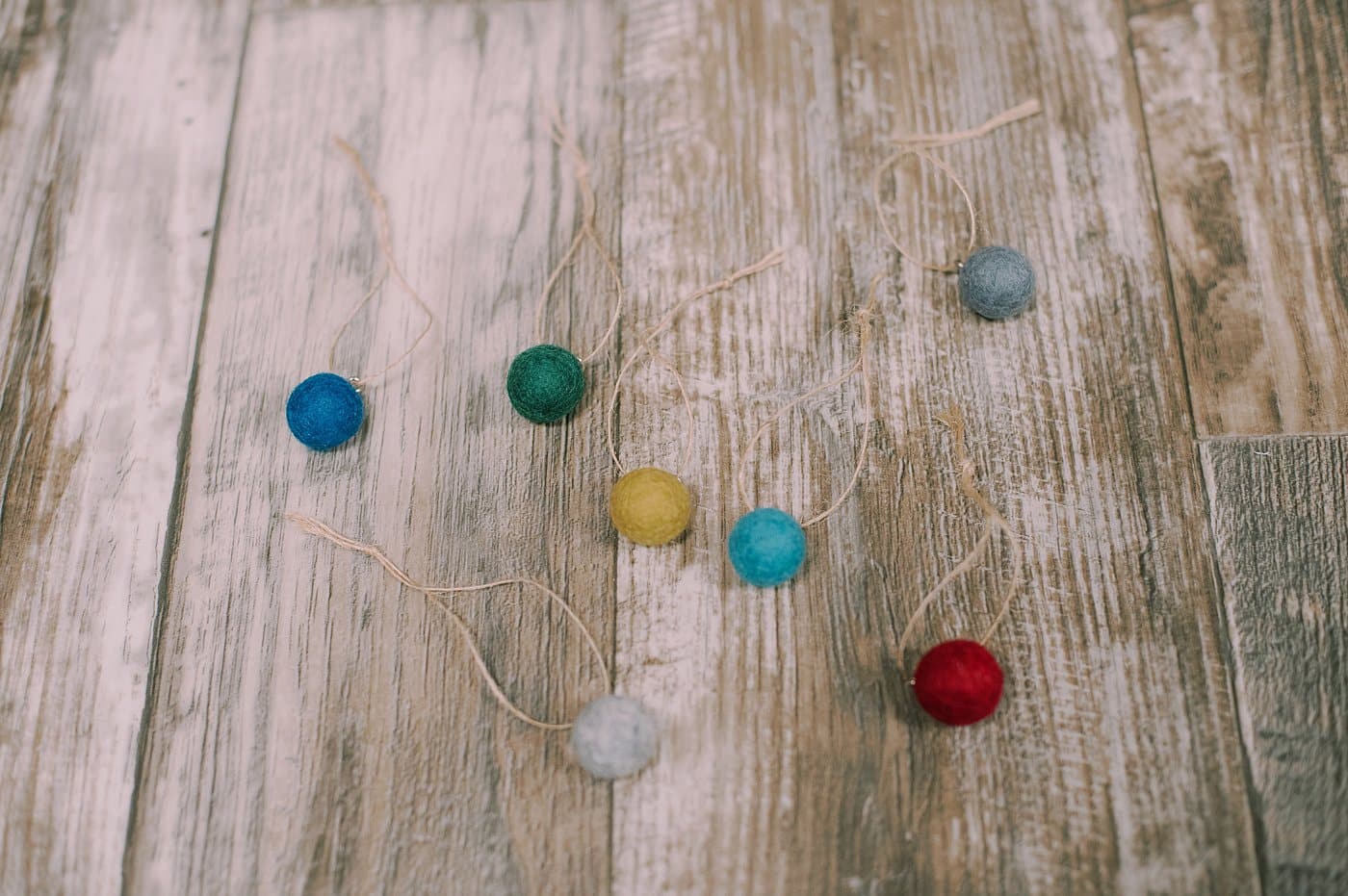 String twine through the loop screwed into the top of each felt ball.