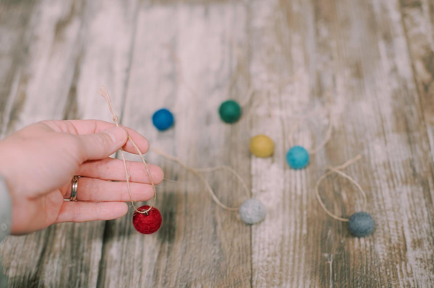 String twine through the loop screwed into the top of each felt ball.