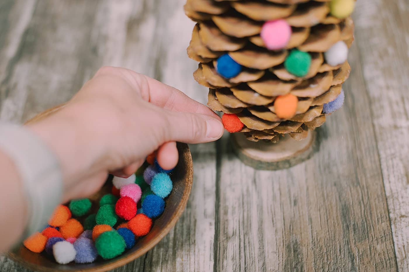 Hot glue pom poms onto the ends of the giant pinecone.