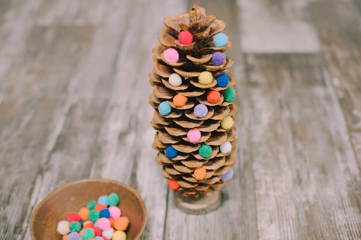 Hot glue pom poms onto the ends of the giant pinecone.