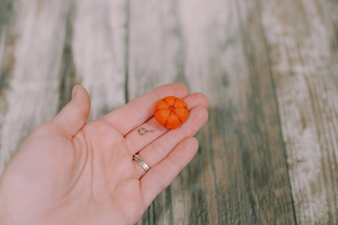 A small eye screw loop and a felt ball pumpkin, ready to be made into an earring.
