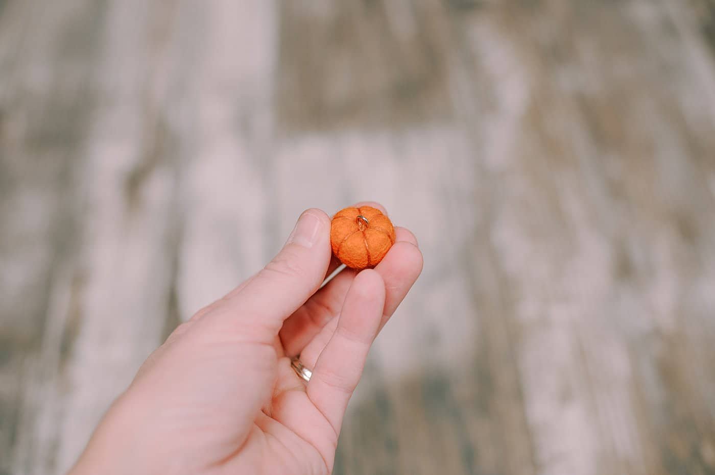 A small pumpkin made using a felt ball, with a metal eye screw on the top.