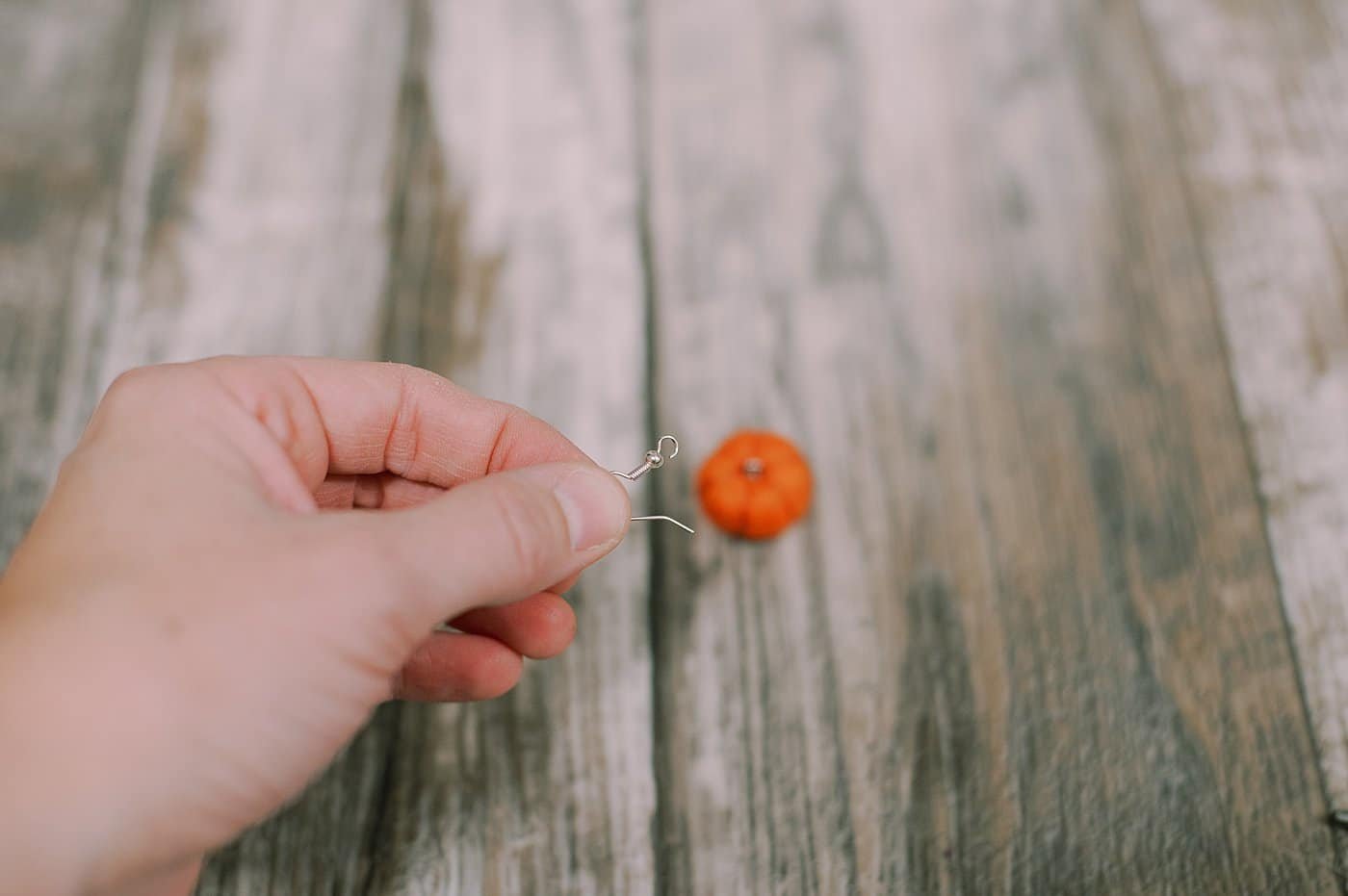 A metal earring hook and a felt ball pumpkin.