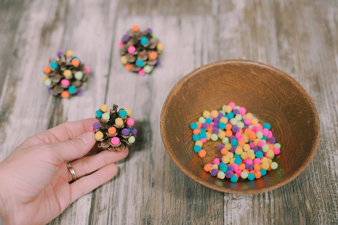 Add pompoms to the mini pine cone christmas tree.