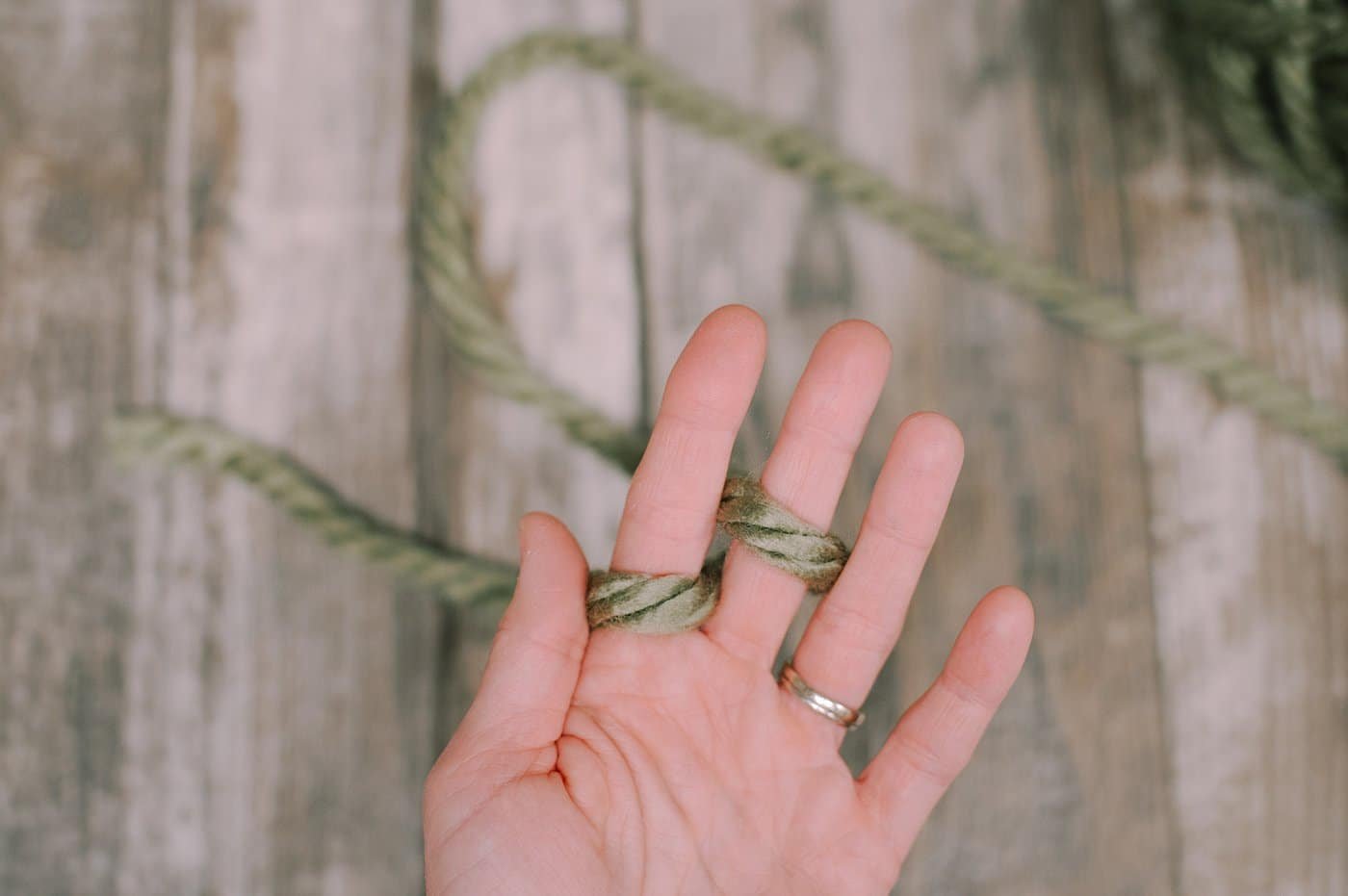 A hand showing finger knitting steps with Chunky Yarn.