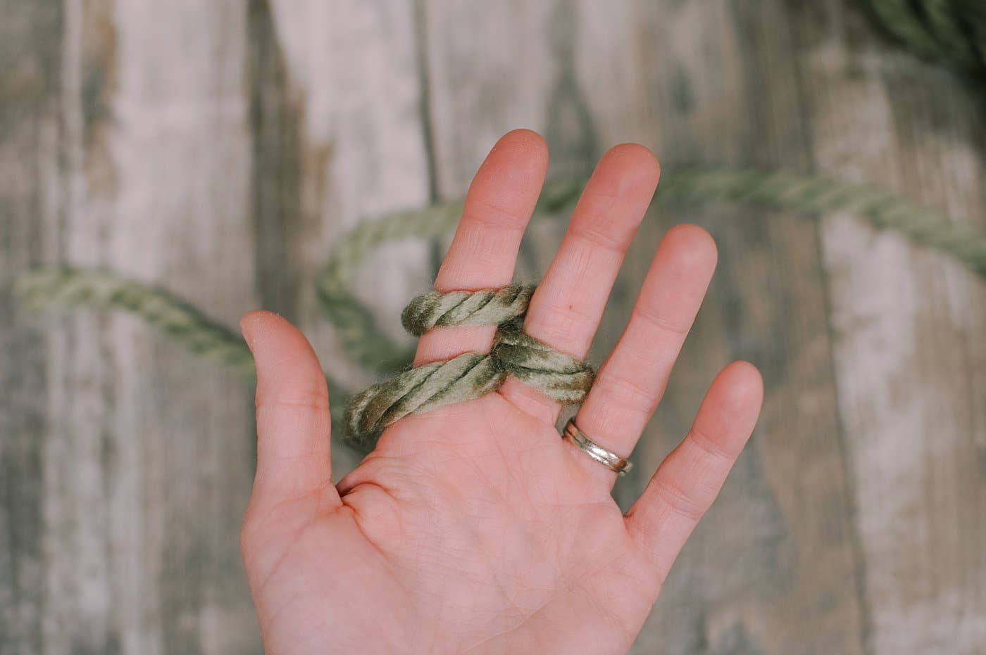 A hand showing finger knitting steps with Chunky Yarn.