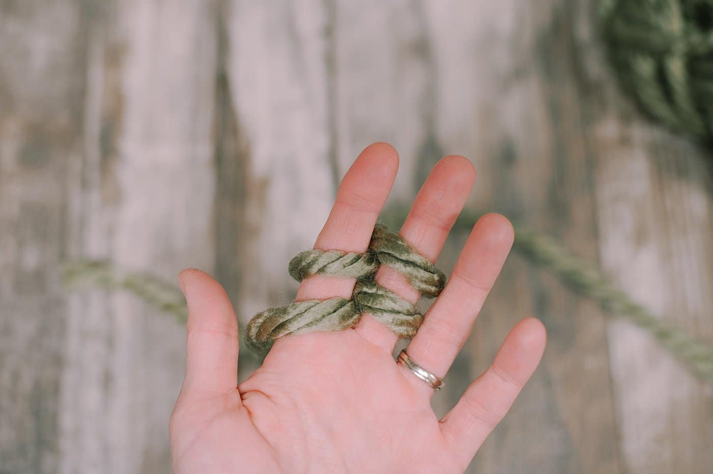 A hand showing finger knitting steps with Chunky Yarn.