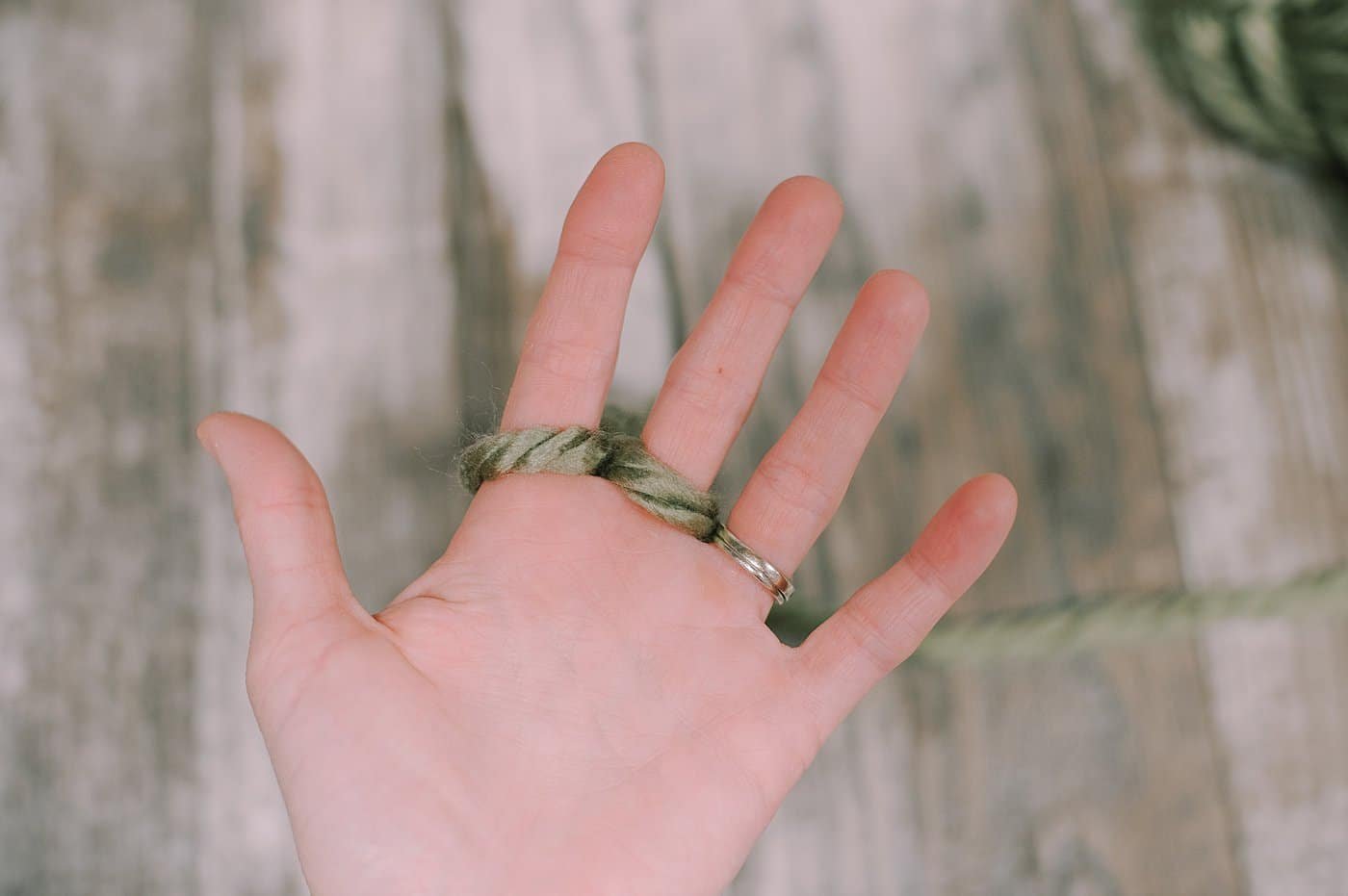 Showing the next steps of finger knitting with chunky yarn.