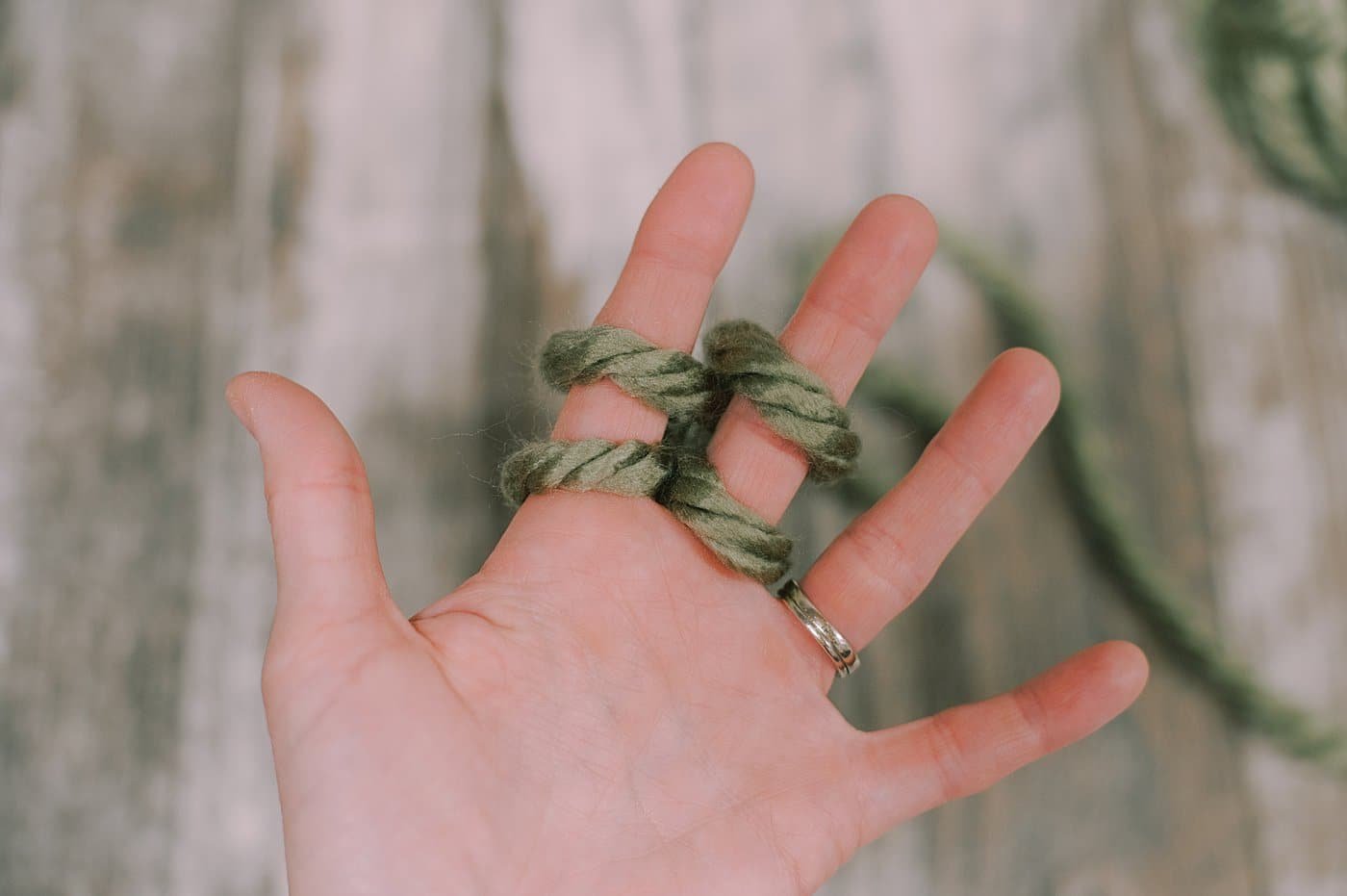 Showing the next steps of finger knitting with chunky yarn.