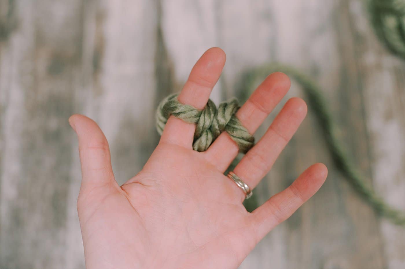 Showing the next steps of finger knitting with chunky yarn.