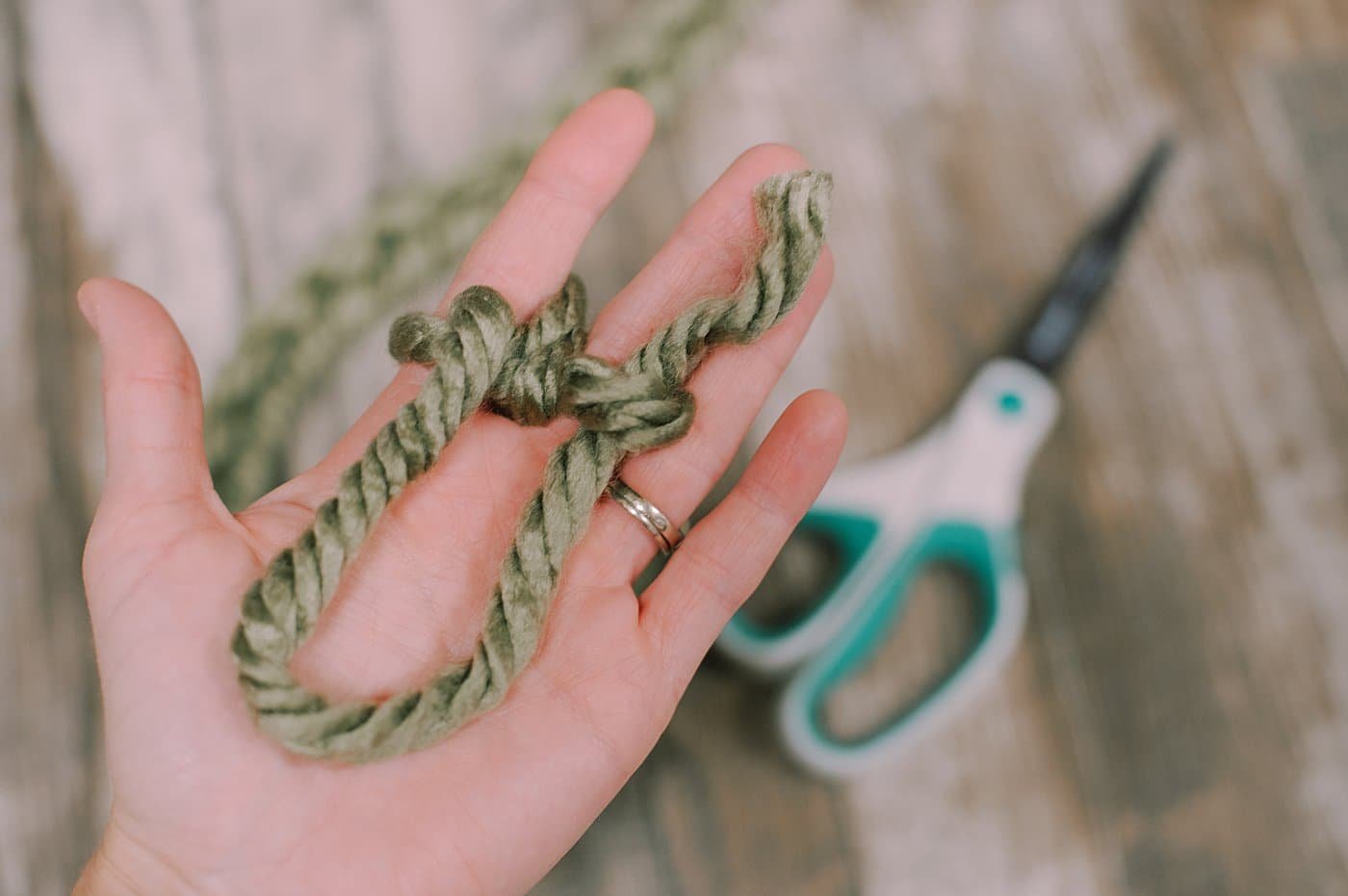 Finishing off a yarn garland made using finger knitting.