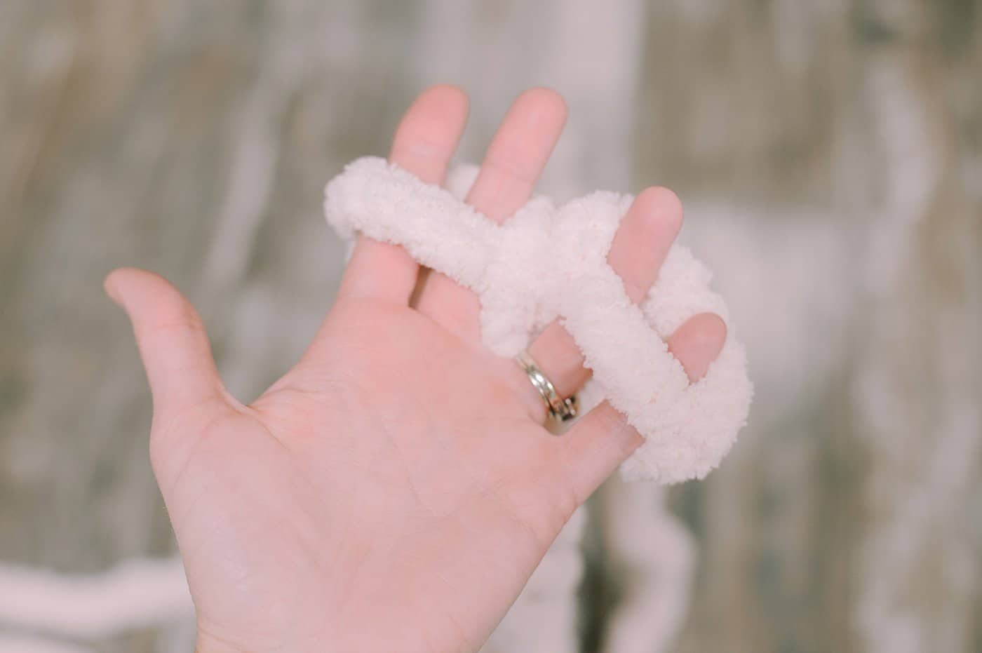 A hand with super chunky yarn wrapped around it for finger-knitting.