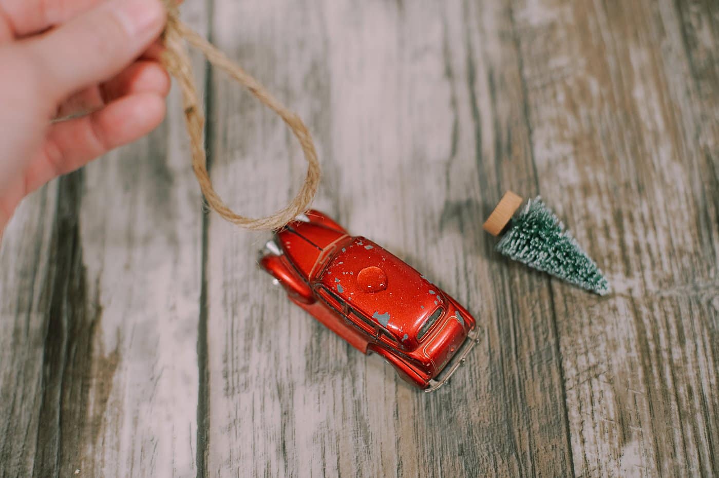 hot glue twine on to the top of the matchbox car as a hanging string