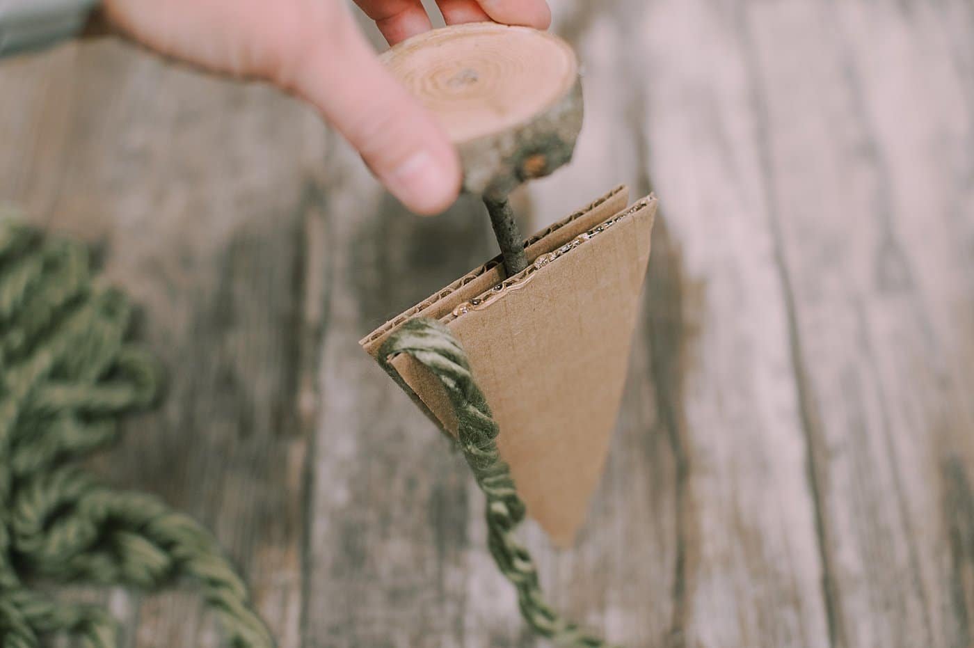 hot glue yarn to the bottom of the cardboard pieces to make a yarn wrapped cardboard tree