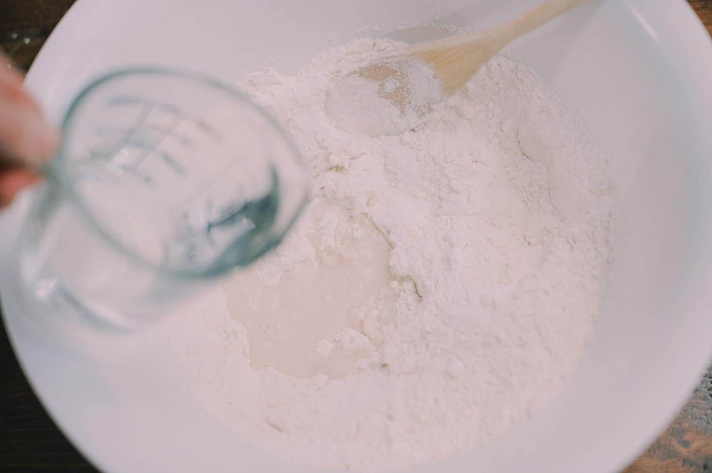 Mixing water into flour and water to make salt dough.