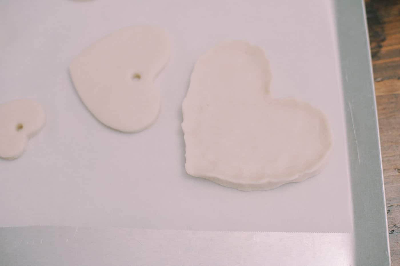 A heart shaped jewelry dish made with salt dough, on a baking sheet.