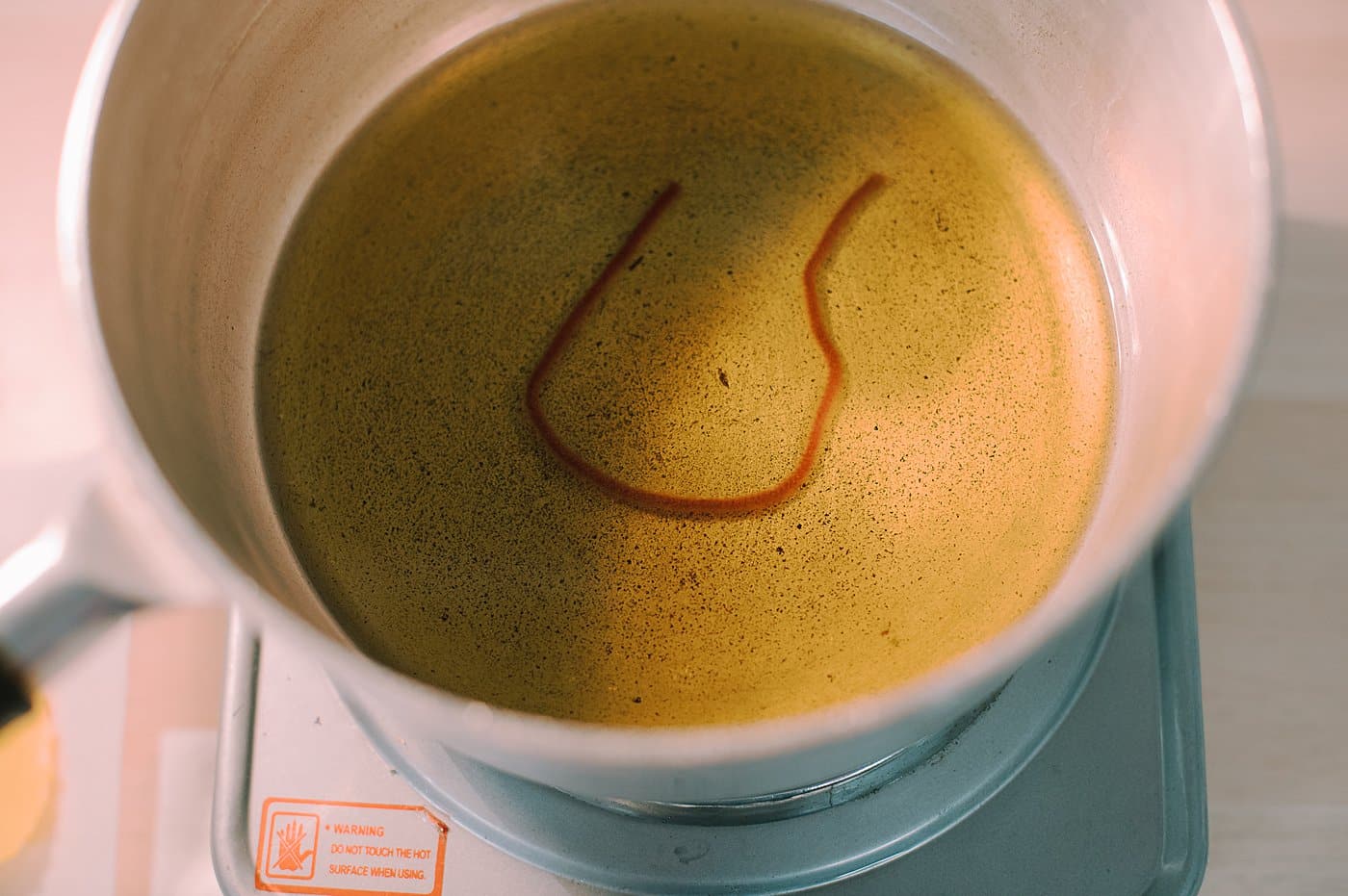 A pot of melted beeswax with a section of yarn laying in it.