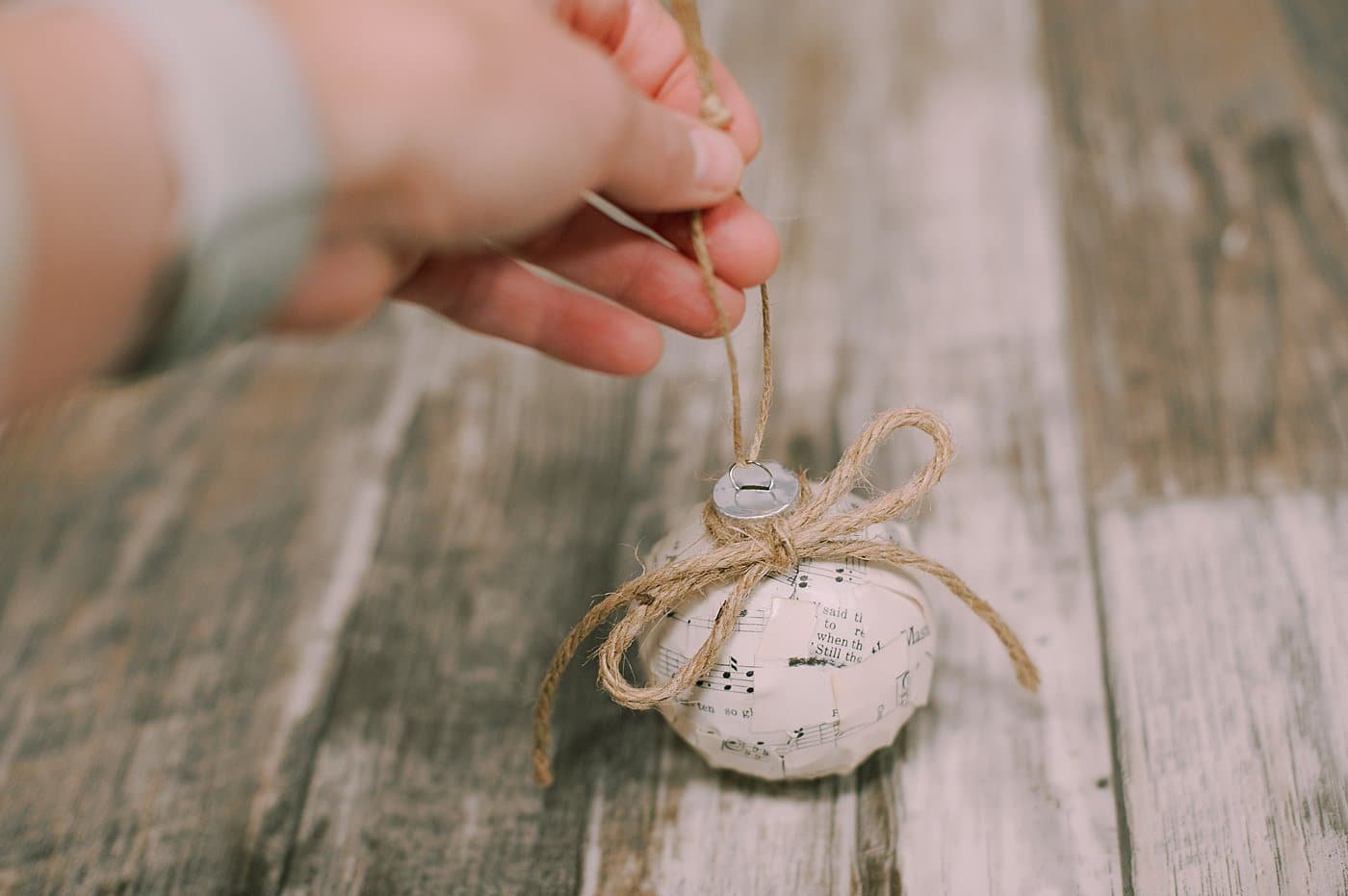 add a piece of twine around the neck of the ornament ball and tie a bow for decoration