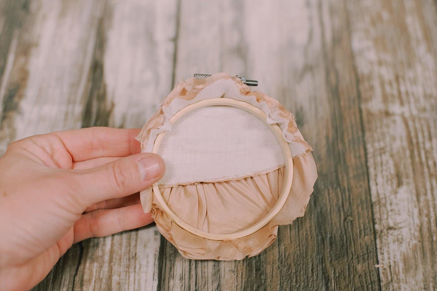 Trim the extra fabric around the edge of the embroidery hoop.