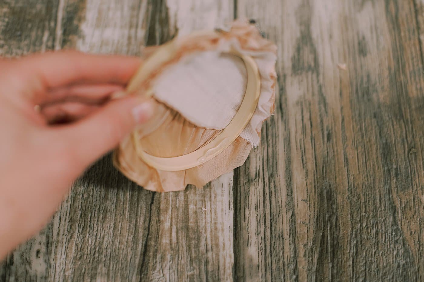 Hot glue the inside of the hoop and push the extra fabric into it.