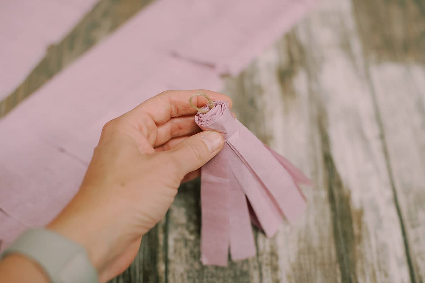 A tissue paper tassel rolled up with a twine hanging string in the middle.