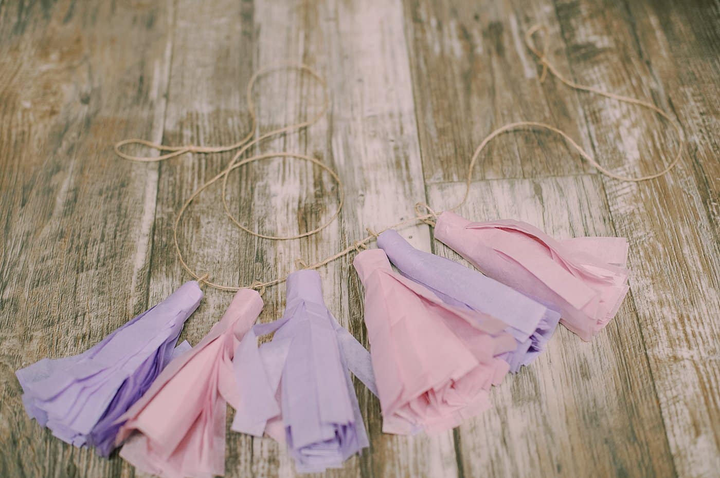 Tissue paper tassels threaded onto a twine string to make a garland.