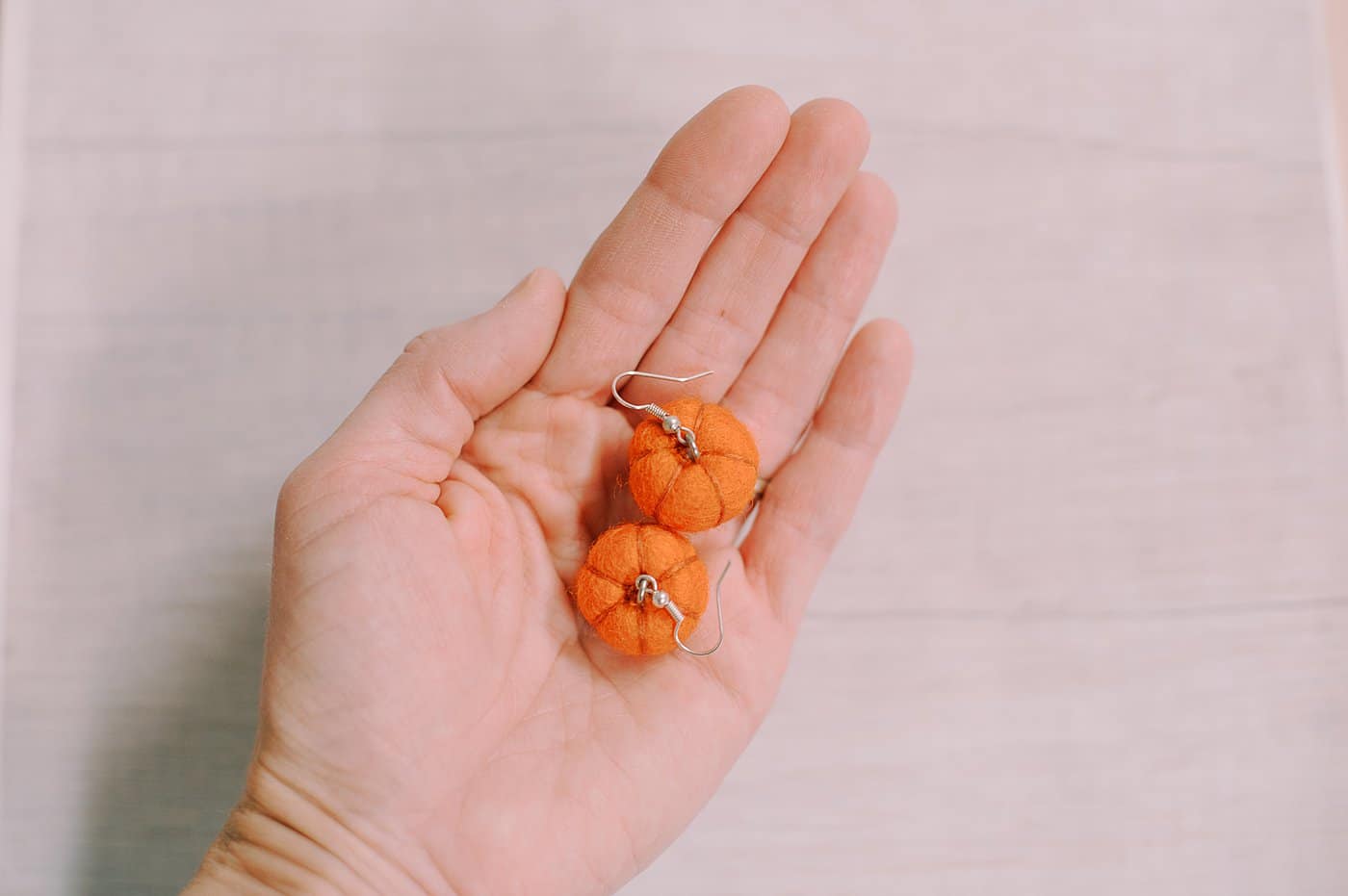 Pumpkin earrings for fall made out of orange felt balls.