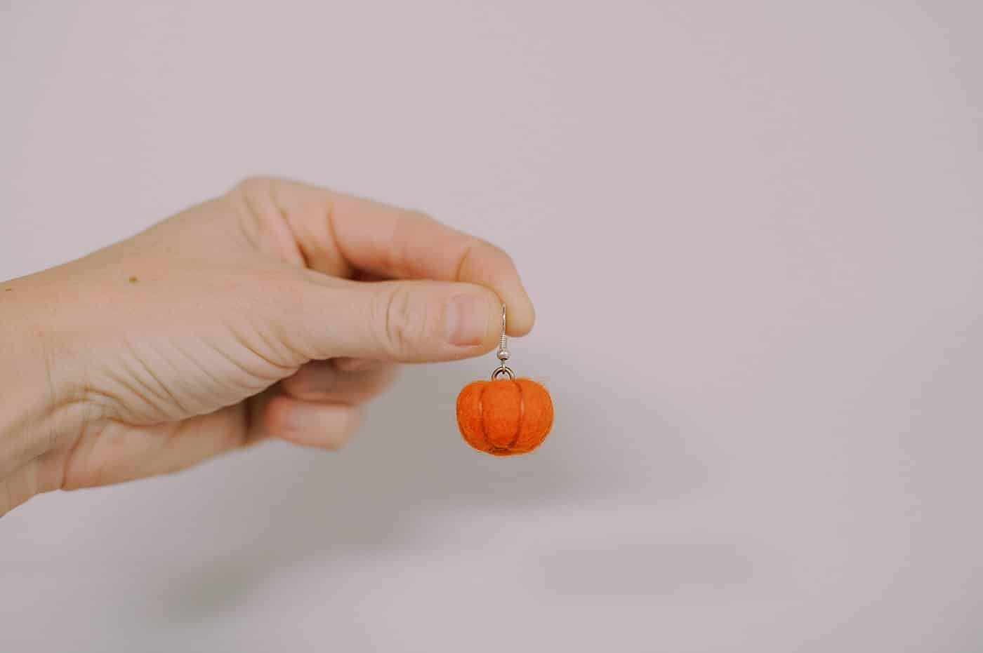 A felt ball pumpkin earring that is perfect for fall or Halloween.