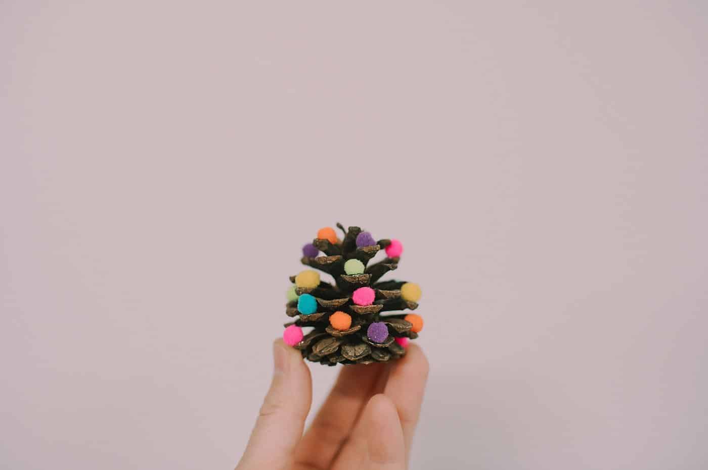 How to make mini pine cone christmas trees with pompom ornaments on them.