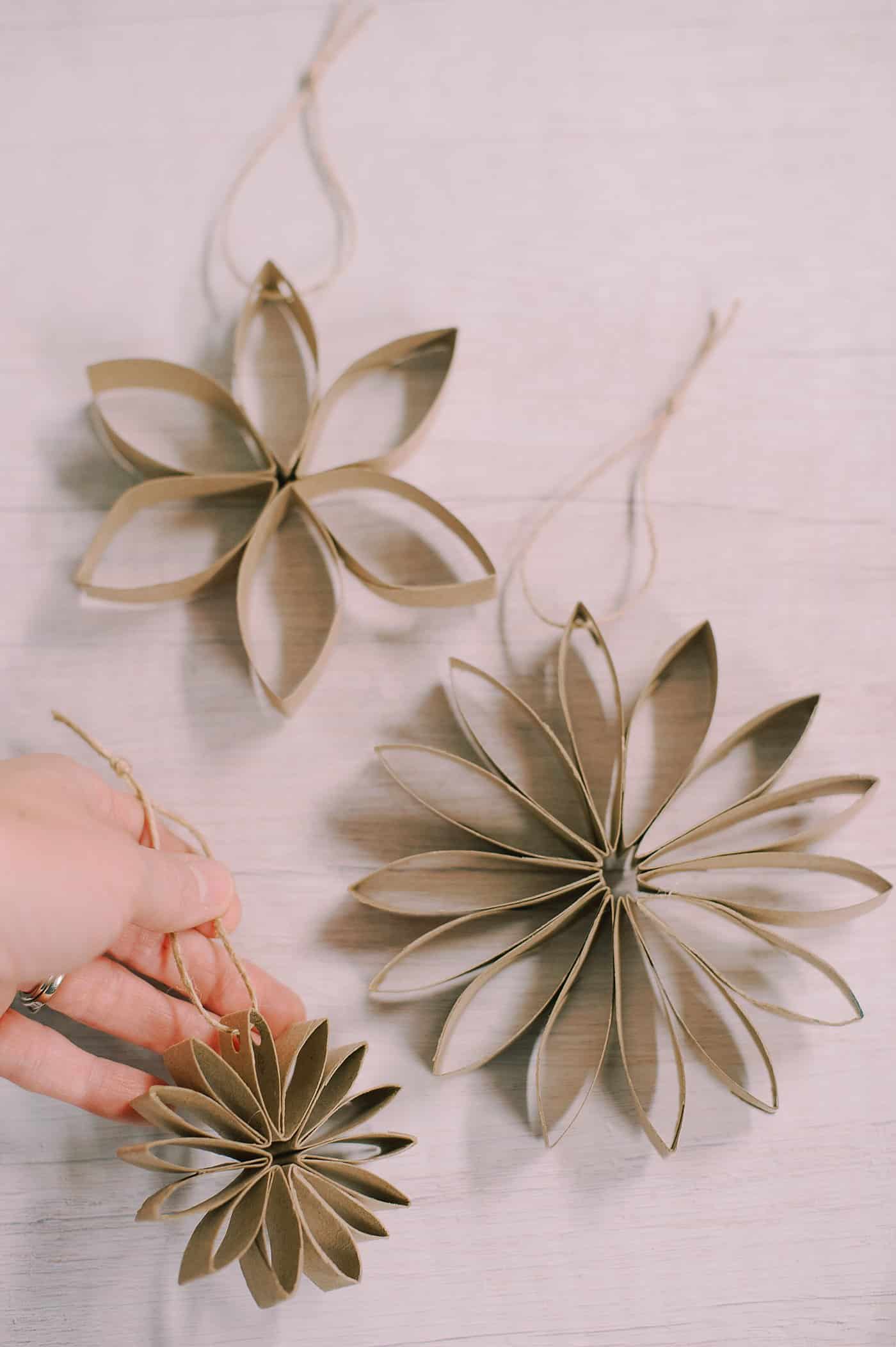Three DIY toilet paper roll flower ornaments with different numbers of petals.