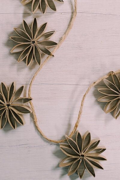 Learn how to make a beautiful rustic chic garland with this simple tutorial, showing you how to make a DIY toilet paper tube flower garland, using old recycled toilet paper rolls!
