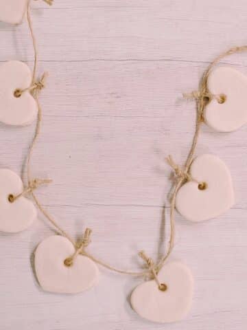 Learn how to make a salt dough heart garland in this easy DIY tutorial. All you need to make salt dough is salt, flour, and water. Plus a straw to punch the hole and twine to hang them up!