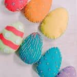 Colorful felt Easter eggs with embroidered stitching around the edges and as designs on the front.