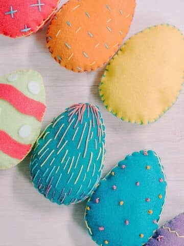 Colorful felt Easter eggs with embroidered stitching around the edges and as designs on the front.