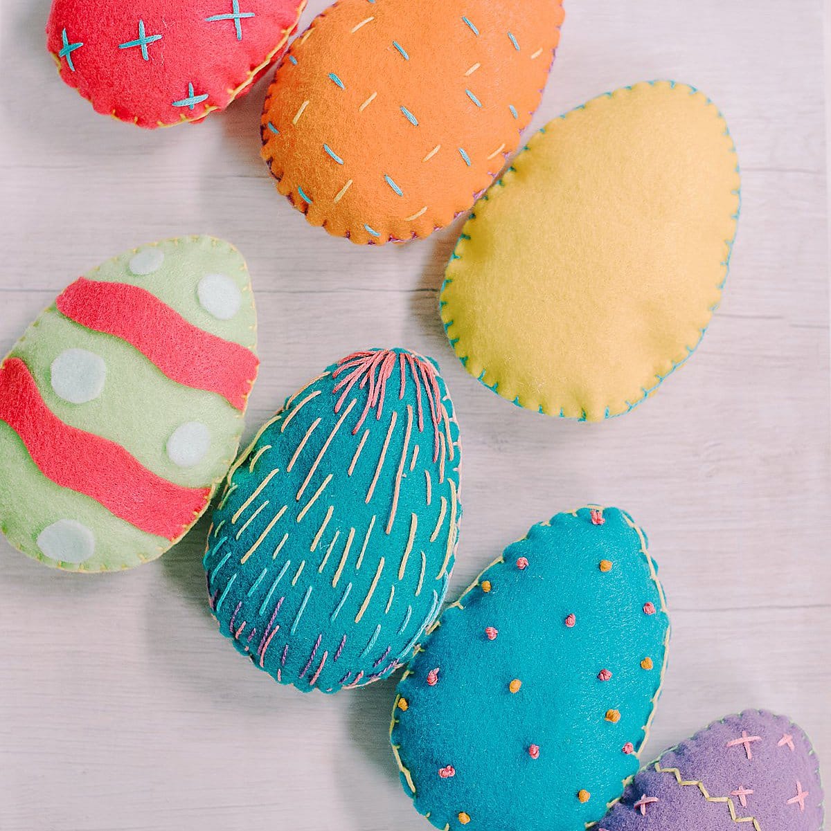 Colorful felt Easter eggs with embroidered stitching around the edges and as designs on the front.